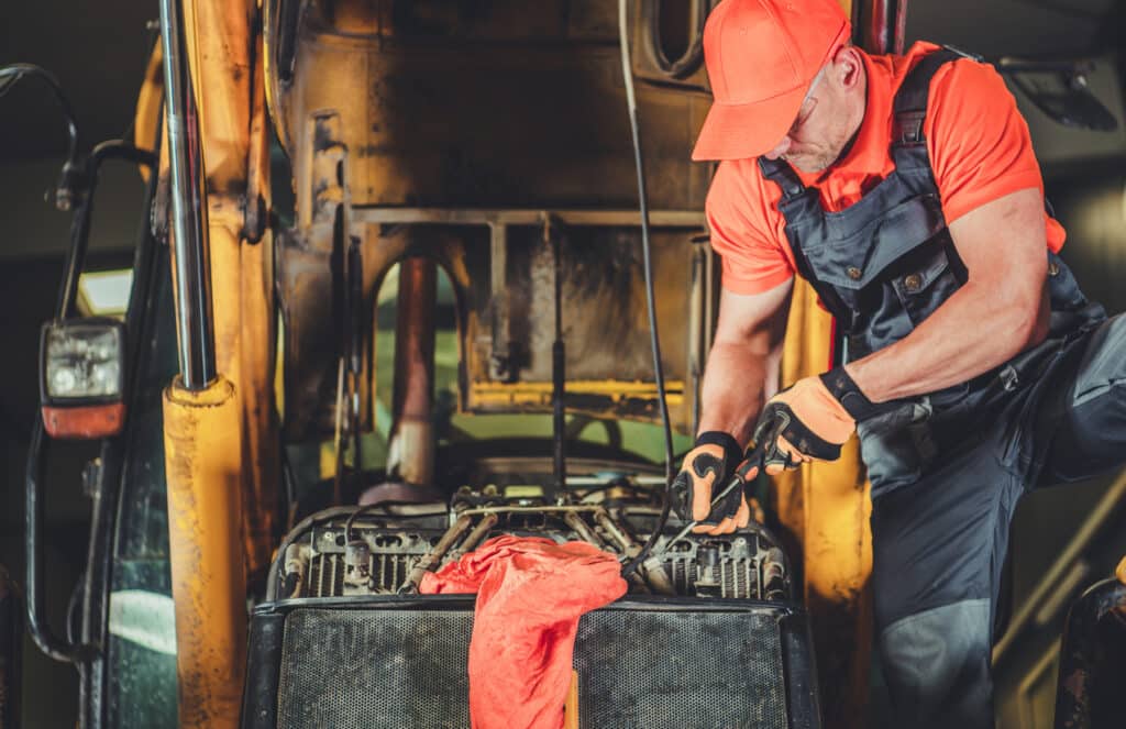 Technician repairing heavy equipment engine part during routine maintenance